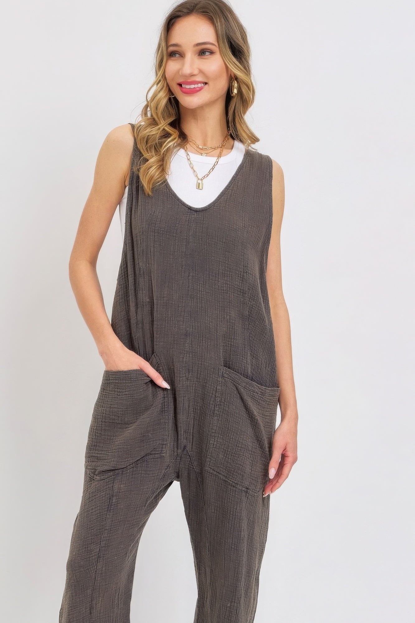 Woman wearing mineral washed summer jumpsuit with oversized patch pockets and adjustable straps.