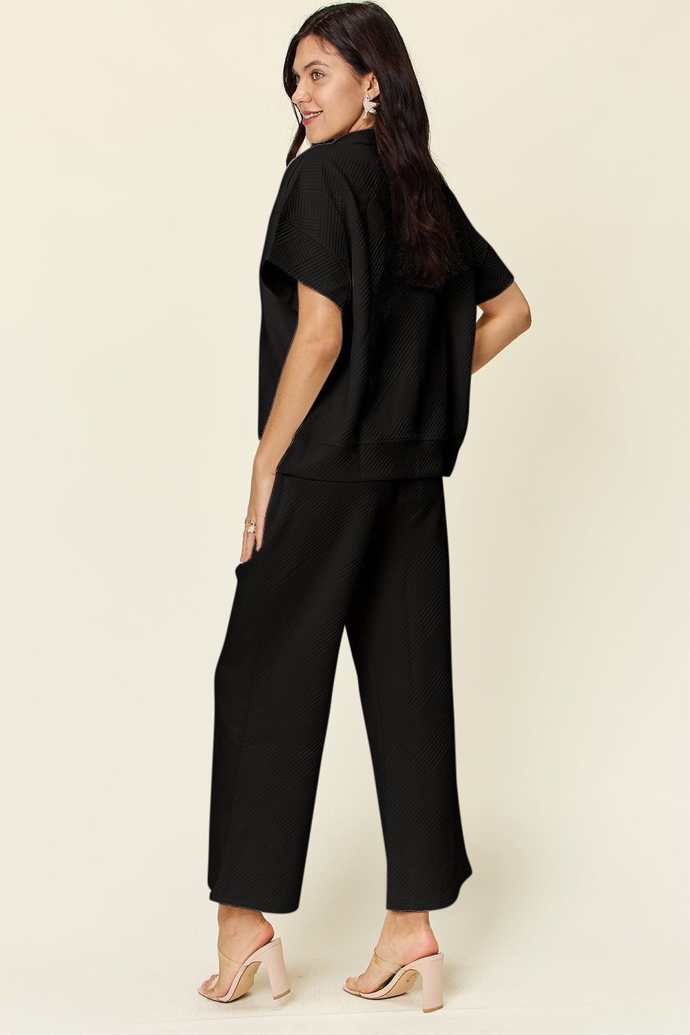 Woman wearing black texture half zip short sleeve top and pants set, pocketed, with drawstring, slightly stretchy fit.