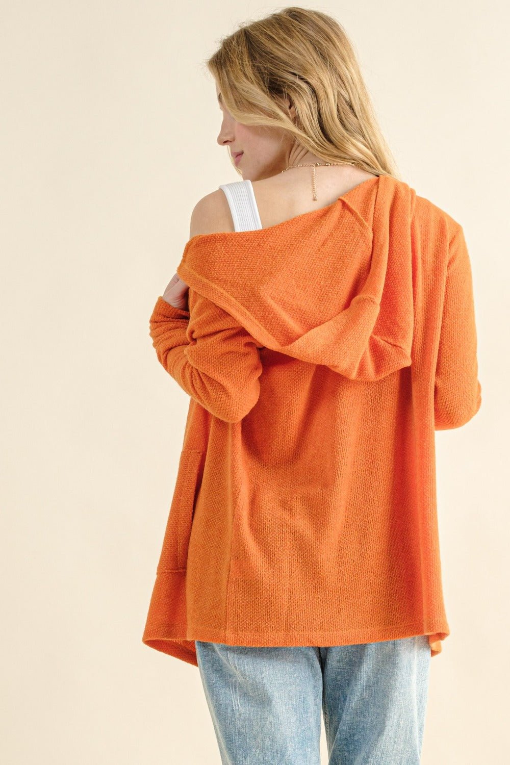 Woman wearing orange thermal hooded open front cardigan with pockets, not lined, made of 96% polyester and 4% spandex.