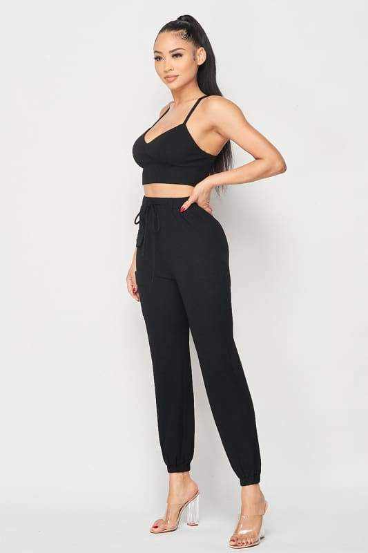 Stylish black ribbed two-piece set with cropped cami and joggers, made of polyester-spandex blend, elegant and comfortable fashion.