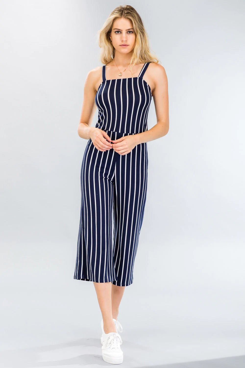 Woman wearing a striped wide-leg capri jumpsuit, sleeveless with a stretch knit fabric and allover stripe pattern.