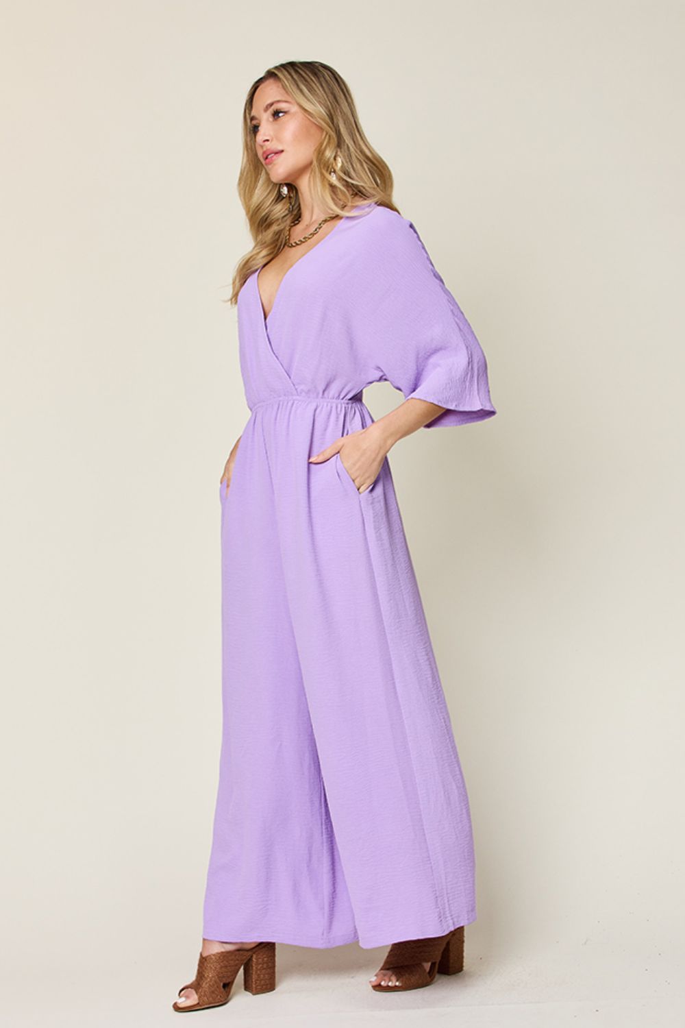 Lavender surplice wide leg jumpsuit with pockets, featuring tied and ruched design, made from 95% polyester and 5% spandex.