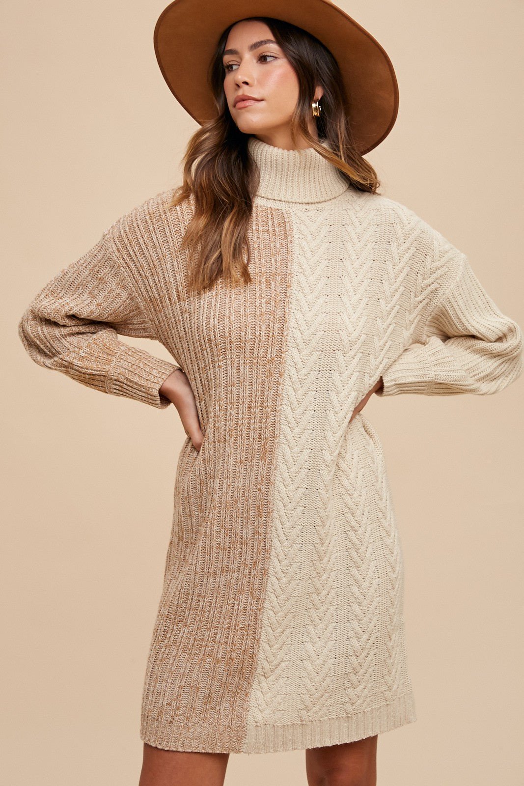Woman wearing winter color block turtleneck sweater dress, featuring ribbed design, in neutral tones, with a stylish hat.