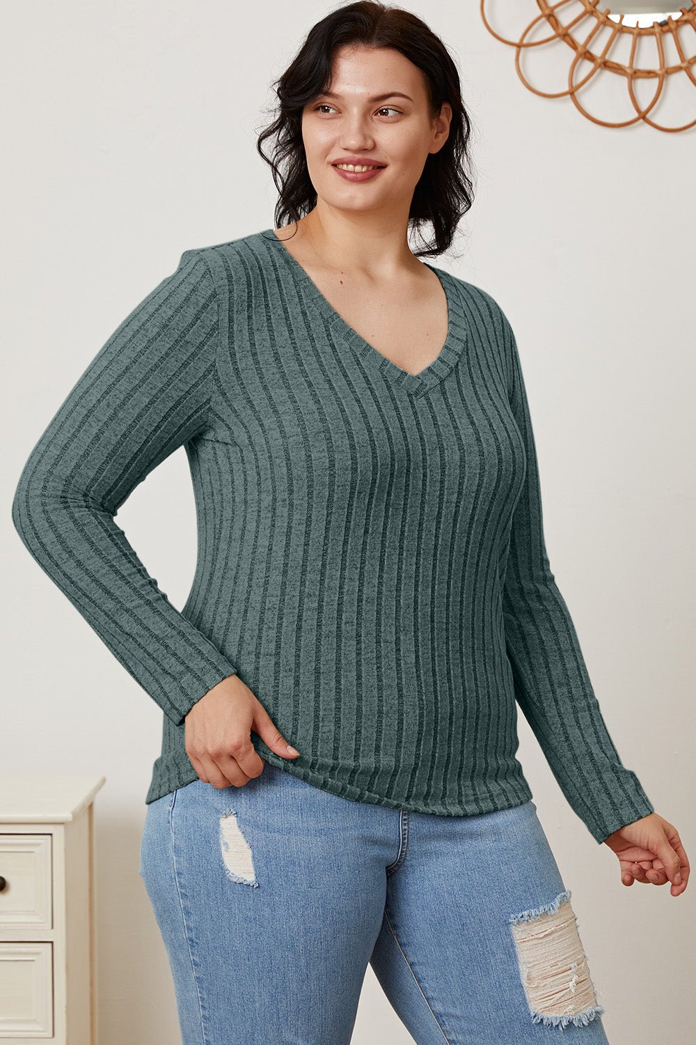Woman wearing Basic Bae ribbed V-neck long sleeve T-shirt in green, paired with distressed jeans, standing in a casual setting.