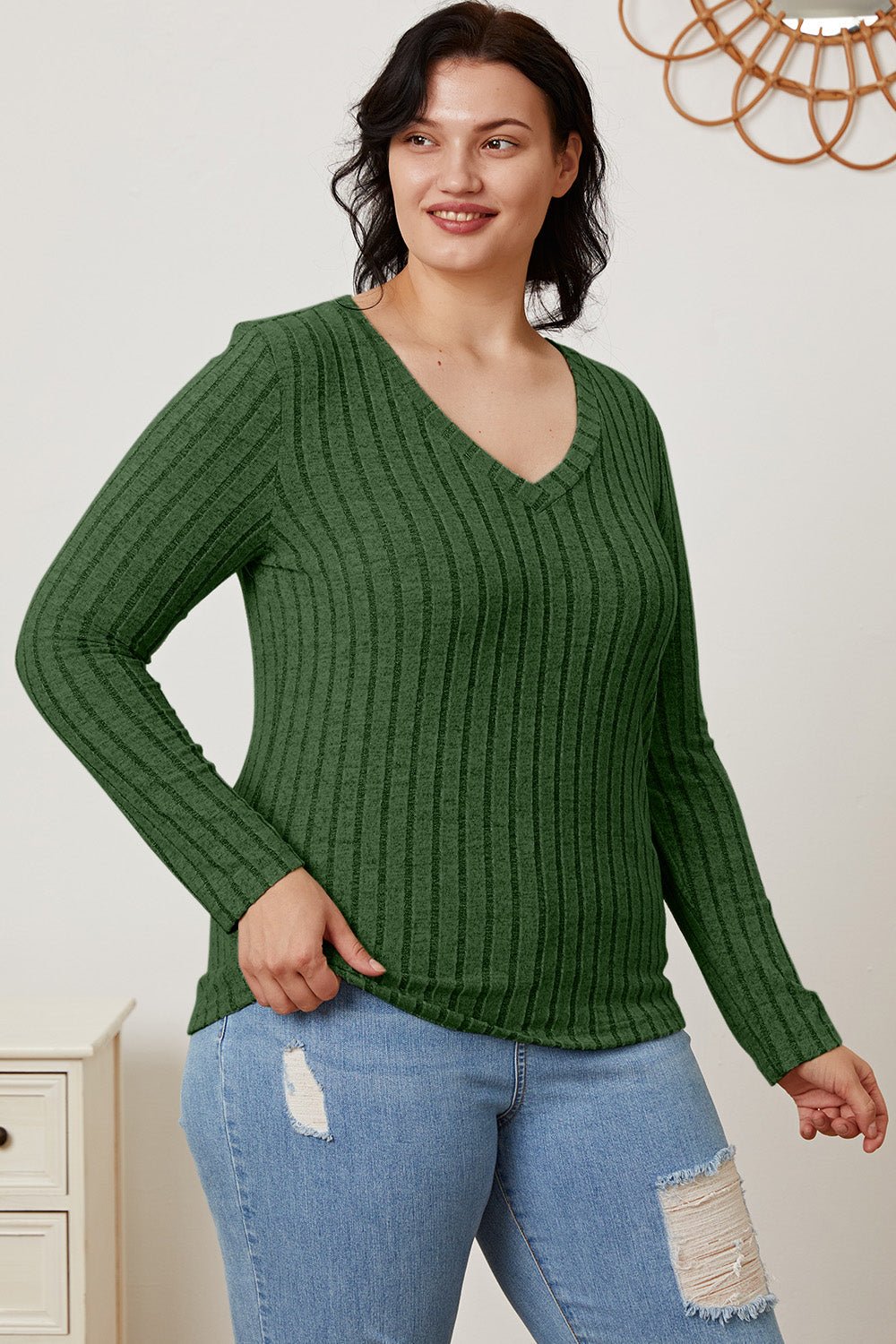 Woman wearing Basic Bae Full Size Ribbed V-Neck Long Sleeve T-Shirt in green, paired with distressed jeans. Fashion and style.