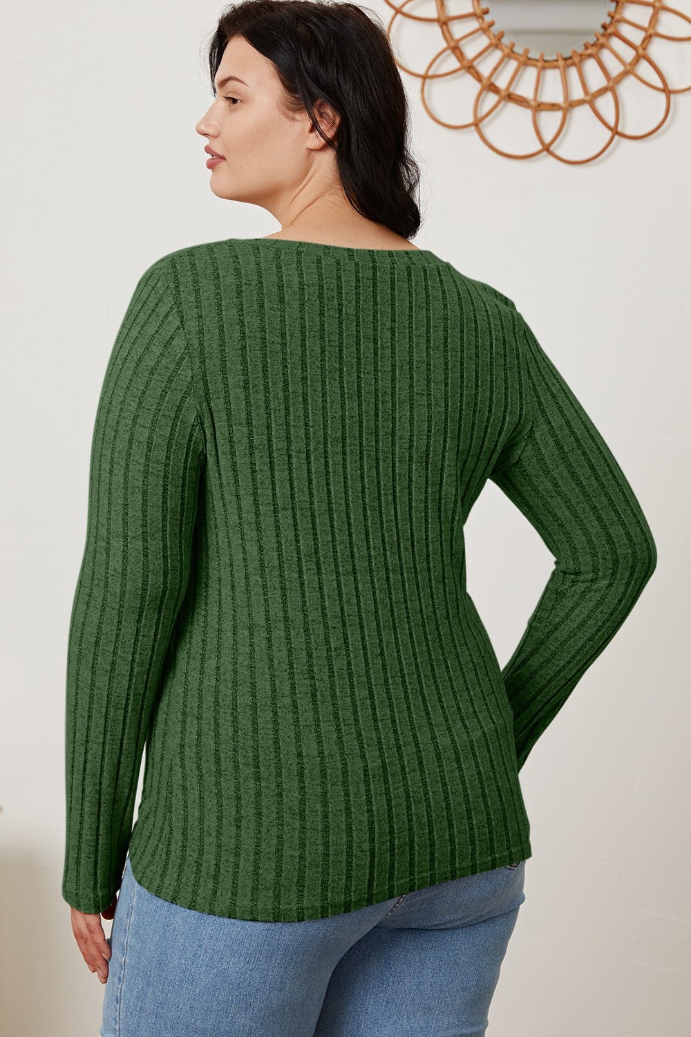 Woman wearing green ribbed V-neck long sleeve T-shirt, back view, paired with jeans.