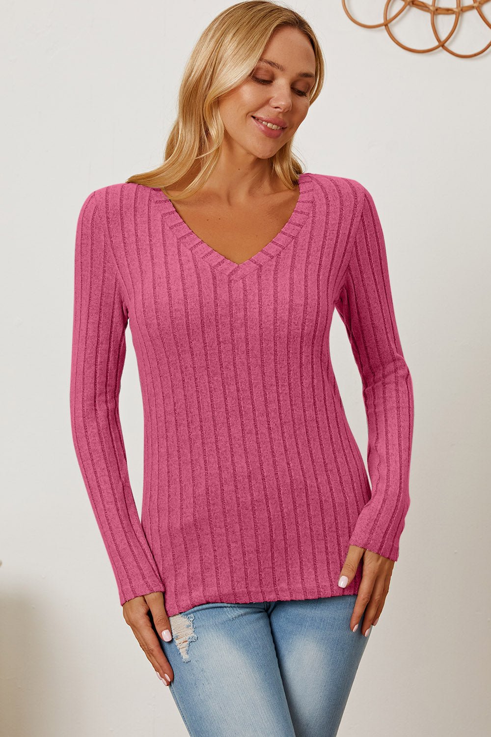 Woman wearing pink Basic Bae full size ribbed V-neck long sleeve T-shirt, styled with light blue jeans.