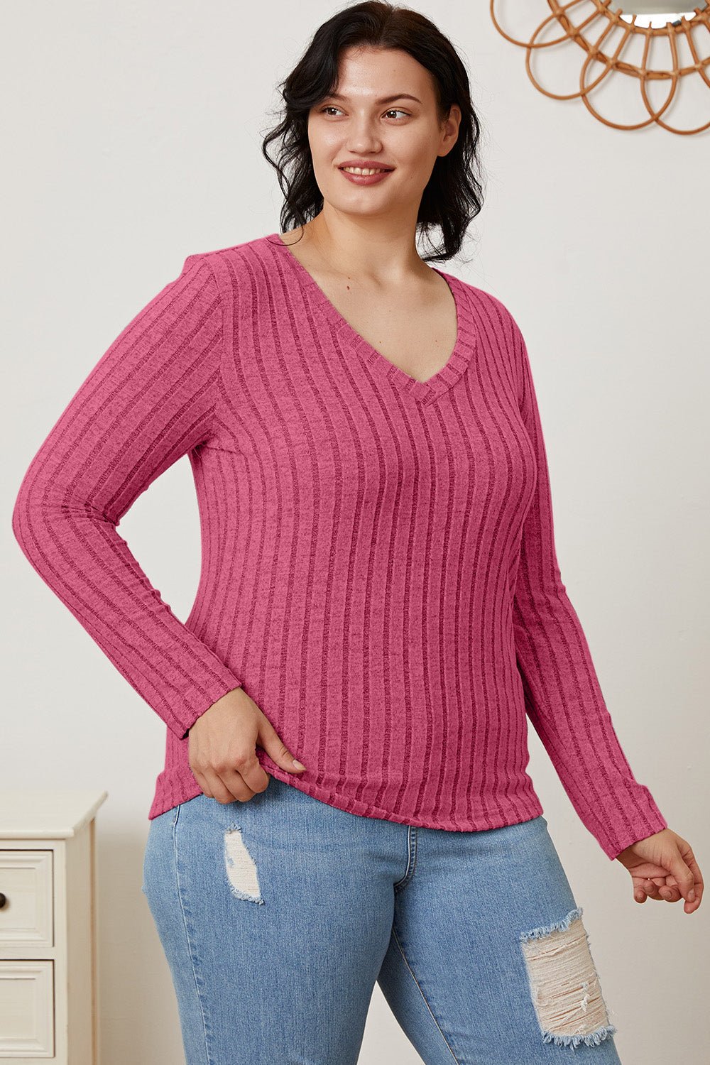 Woman wearing pink ribbed V-neck long sleeve T-shirt with jeans, showcasing stylish casual look.