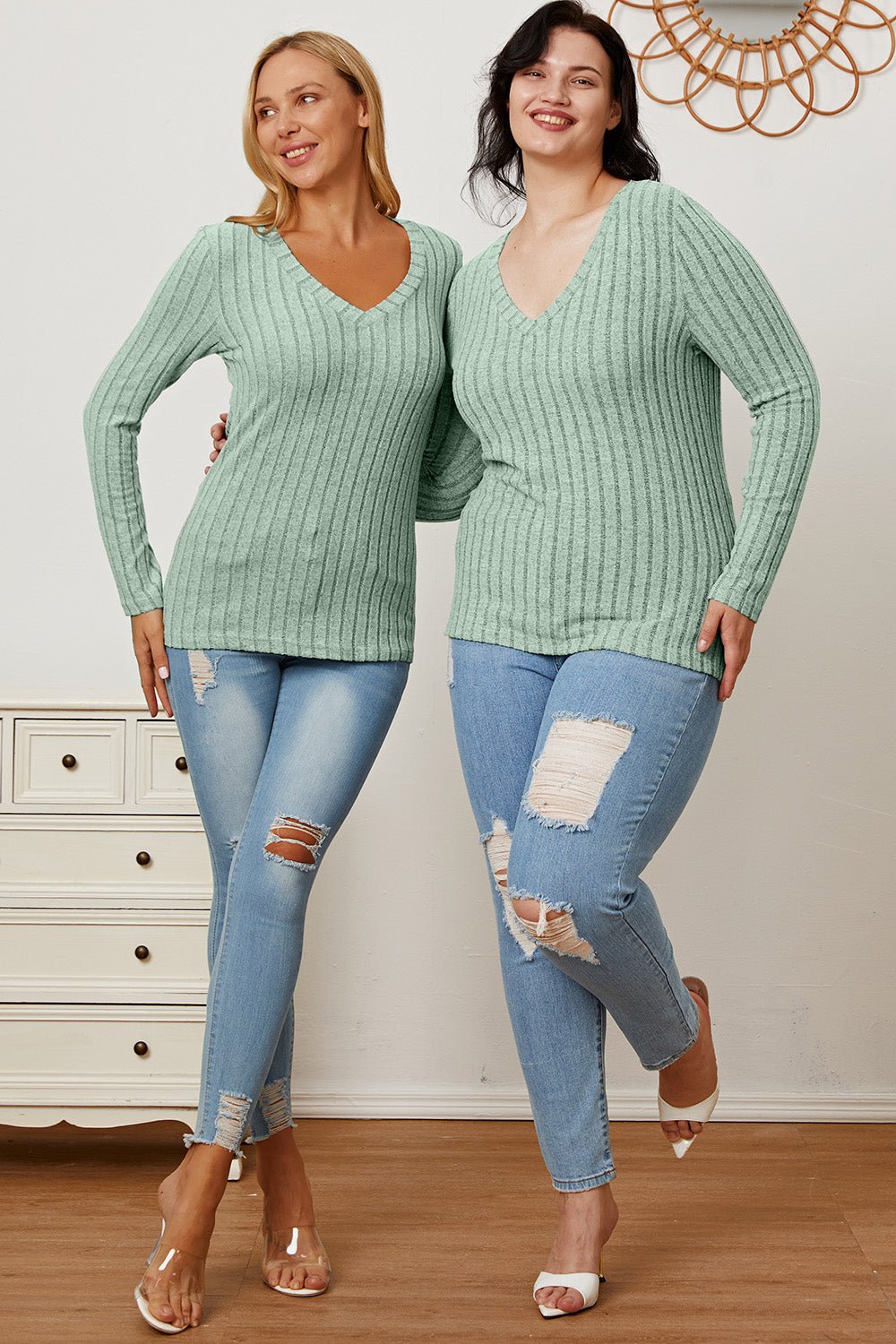 Two women wearing Basic Bae full-size ribbed V-neck long sleeve t-shirts in mint green paired with distressed jeans.